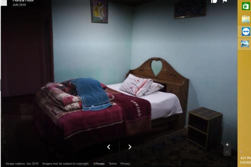 a small bedroom with a bed with a wooden headboard at Hunza Huts Duikar Altit in Baltit