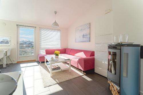 a living room with a pink couch and a table at Three-Bedroom Apartment in Tjørhom