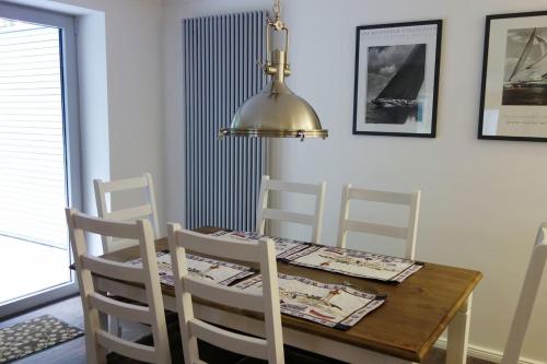 a dining room table with white chairs and a lamp at Schönes Ferienhaus in Maasholm Bad, Ostsee in Maasholm