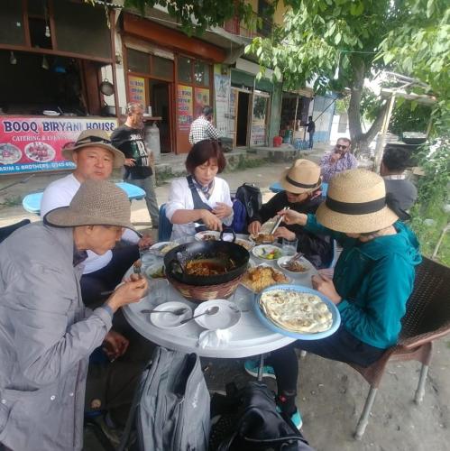 un grupo de personas sentadas alrededor de una mesa comiendo comida en Ali Boq Hotel & Restaurant en Hunza