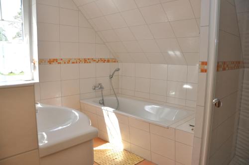 y baño con bañera, aseo y lavamanos. en Ferienhaus Müritzsonne / OG-Appartement en Marienfelde