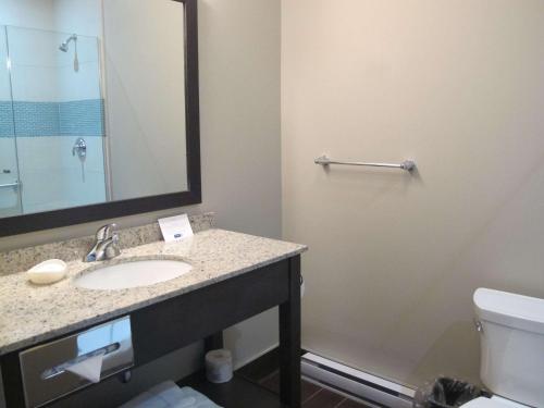 a bathroom with a sink and a toilet and a mirror at Best Western Plus Hotel Montreal in Montreal