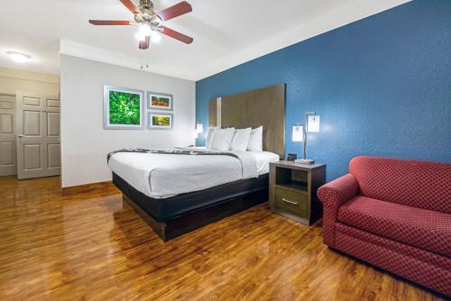 a hotel room with a bed and a red couch at La Quinta Inn & Suite Kingwood Houston IAH Airport 53200 in Kingwood