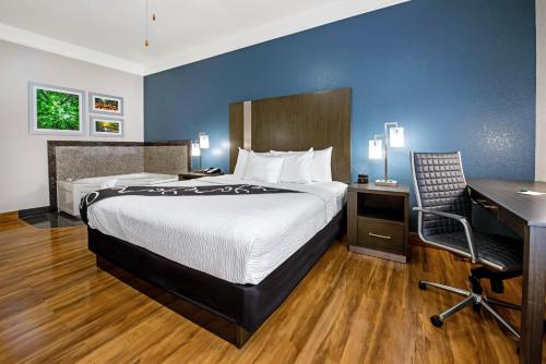 a hotel room with a bed and a desk and a computer at La Quinta Inn & Suite Kingwood Houston IAH Airport 53200 in Kingwood
