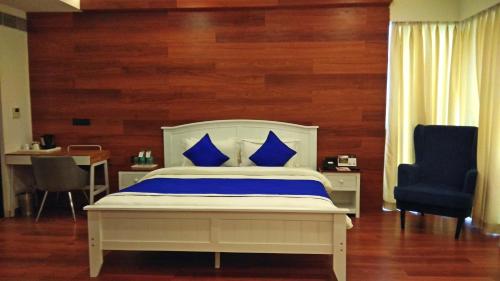 a bedroom with a bed with blue pillows and a chair at Polo Cherrapunjee Resort in Cherrapunji