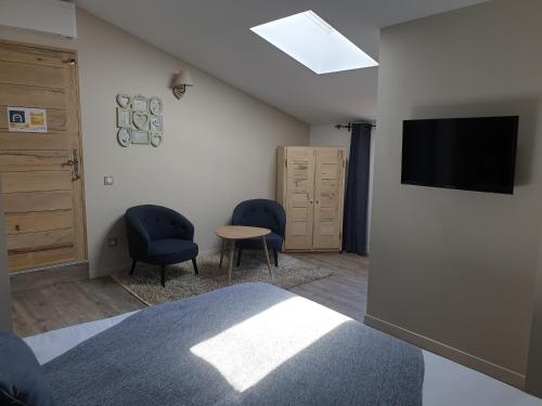 a bedroom with two chairs and a flat screen tv at Mas de Reilhanette in Montbrun-les-Bains