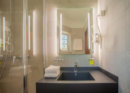 La salle de bains est pourvue d'un lavabo et d'une douche avec un miroir. dans l'établissement Hotel Unione, à Bellinzone