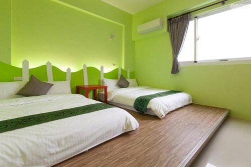 two beds in a room with green walls at 艾兒民宿 l 台東包棟 l 按訂房人數開放房間8-21人 in Taitung City