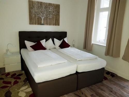 una camera da letto con un letto con cuscini bianchi e rossi di Villa zur schönen Aussicht a Bad Salzuflen