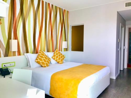Un dormitorio con una cama con almohadas. en Hotel 3K Faro Aeroporto en Faro