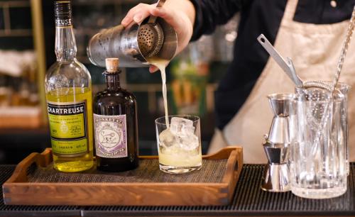 a person pouring a drink into a glass at Stora Hotellet i Fj&auml;llbacka in Fj&auml;llbacka