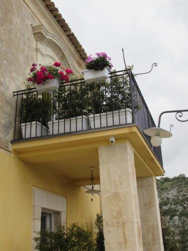 a balcony with pink flowers on a building at Bed and Breakfast Terra del Sole Ibla in Ragusa