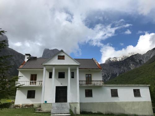 a white house with mountains in the background at Kulla e Sadri Lukes in Theth