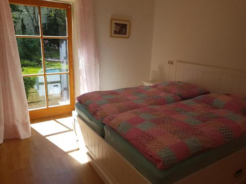 a bed in a bedroom with a window and a bedspread at Martina's Place Bed & Breakfast in Rottenbuch