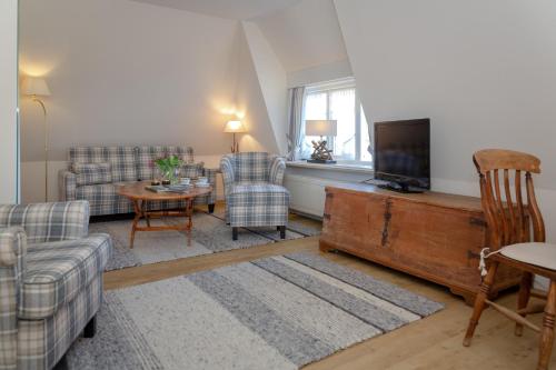 a living room with a couch and a tv at Boutiquehotel Seiler Hof Keitum in Keitum