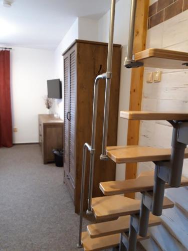 a room with wooden stairs in a room with a desk at Rodinný pension U Soudku in Rudník
