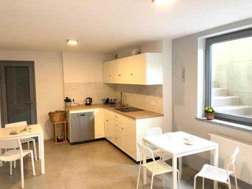 a kitchen with white cabinets and a table and chairs at Willa Alcala in Pobierowo