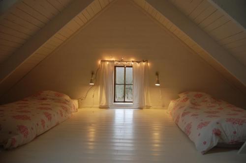 a attic room with two beds and a window at Lillstugan in Torestorp