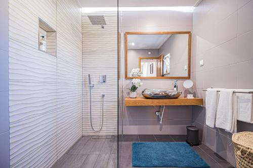a bathroom with a shower with a sink and a mirror at Buganvilias Do Meco Guest house in Sesimbra