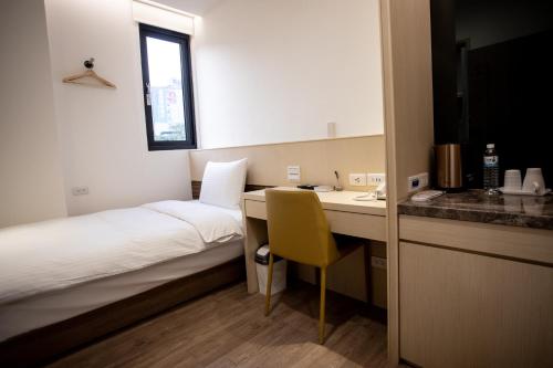 a small hotel room with a desk and a bed and a kitchen at Beauty Avenue Inn in Kaohsiung