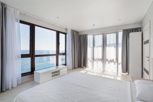a bedroom with a large white bed and large windows at Sun Ray in Yalta