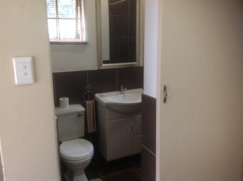 a bathroom with a white toilet and a sink at Duvet & Crumpets in Pietermaritzburg