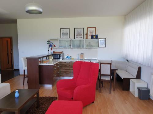 sala de estar con silla roja y cocina en Apartman 0204 Donovaly, en Donovaly