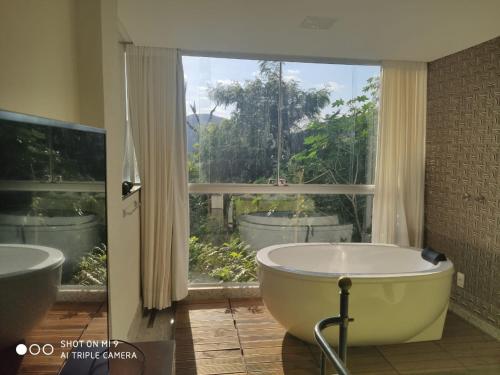 uma casa de banho com banheira e uma grande janela em Loft Espaço Vila da Serra em Nova Lima