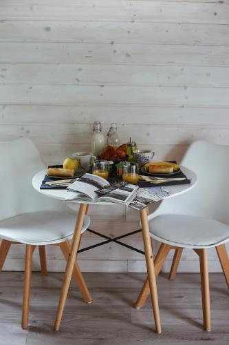 Una mesa con una bandeja de comida encima y dos sillas. en Au Cap Norwoe, en Saint-Quentin-en-Tourmont