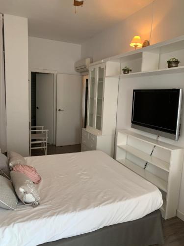 a bedroom with a bed and a flat screen tv at Apartamento primera línea de playa in Port Saplaya