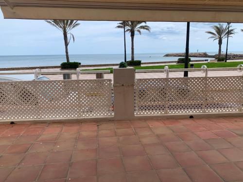 two white benches sitting next to the beach at Apartamento primera línea de playa in Port Saplaya