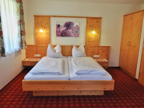 a bedroom with a large bed with white sheets at Schieplechnerhof in Schladming