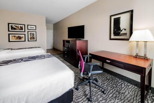 a hotel room with a bed a desk and a computer at La Quinta by Wyndham DFW Airport West - Bedford in Bedford