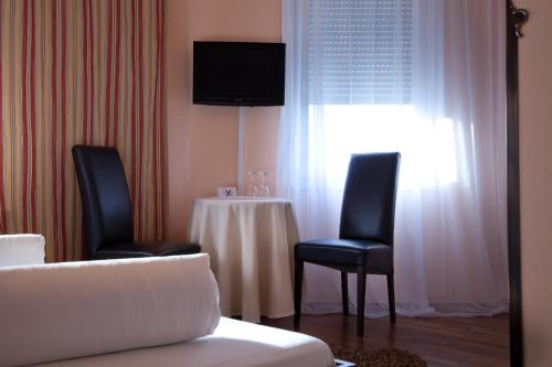 ルートヴィヒスブルクにあるHotel Rivieraのテーブル、椅子2脚、テレビが備わる客室です。