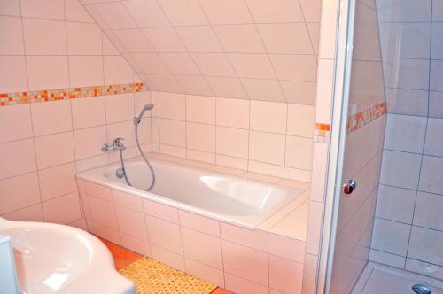 y baño con bañera, aseo y lavamanos. en Ferienhaus Müritzbrise / OG-Appartement, en Marienfelde