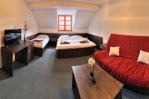 Habitación con 2 camas, sofá y TV. en Štiřínská stodola u Prahy, en Kamenice