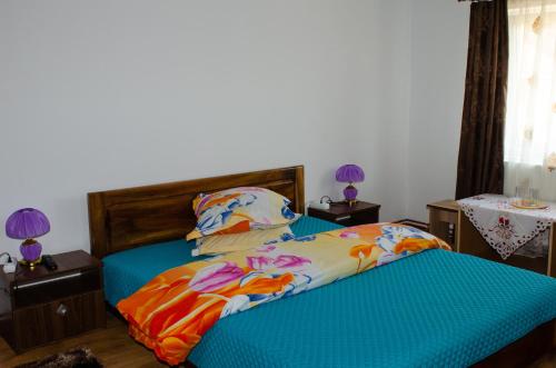 - une chambre avec un lit avec des draps bleus et 2 tables dans l'établissement Pensiunea Aly, à Bumbesti Pitic