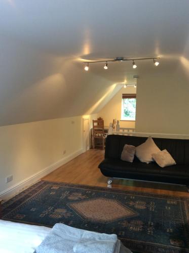 Melbury في Rudgwick: غرفة معيشة مع أريكة سوداء وسجادة