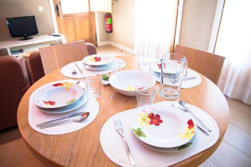a wooden table with white plates and forks and glasses at Apartamentos Bergantes in Ortells