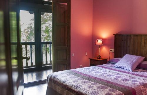 um quarto com paredes cor-de-rosa, uma cama e uma janela em La Casería de Los Hevia 1 y 2 em Arriondas