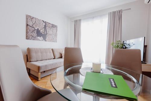 uma sala de estar com uma mesa de vidro e cadeiras em 4Seasons﻿ Apartments Cracow em Cracóvia