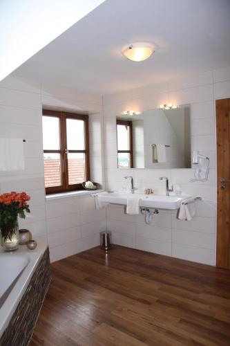 a white bathroom with two sinks and a mirror at Hotel - Restaurant Eberlwirt in Bruckberg