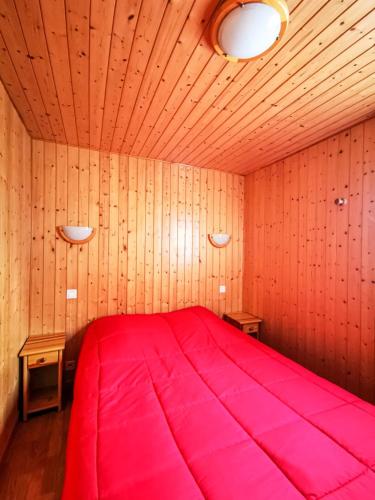 ein großes rotes Bett in einem Zimmer mit Holzwänden in der Unterkunft PRL Le Védrignans in Saillagouse
