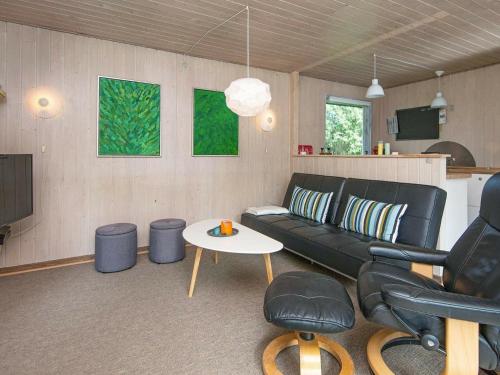 sala de estar con sofá negro y mesa en 6 person holiday home in R m en Bolilmark