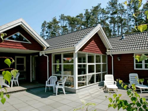 a house with a patio with white chairs on it at Modern Holiday Home in Aakirkeby with Sauna in Vester Sømarken