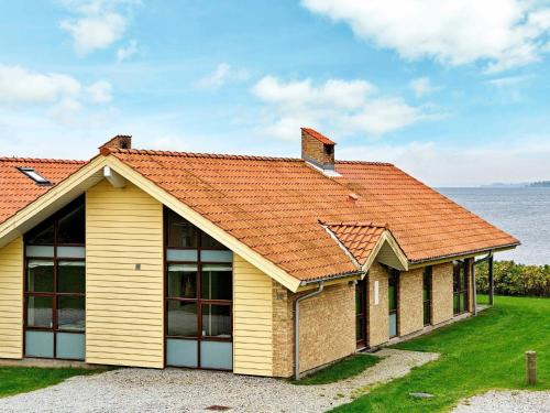 una casa amarilla con techo naranja junto al agua en 6 person holiday home in Egernsund, en Egernsund