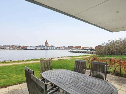 a wooden table and chairs with a view of the water at 5 person holiday home in Stege in Stege