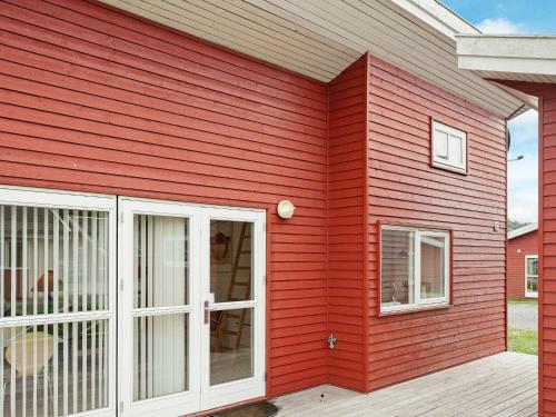 een rood huis met een witte deur en ramen bij 4 person holiday home in Gudhjem in Gudhjem