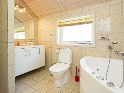 a bathroom with a toilet and a tub and a sink at Three-Bedroom Holiday home in Højby 1 in Højby