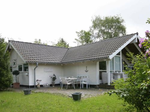 a white house with a patio and a table at 6 person holiday home in Dronningm lle in Gilleleje